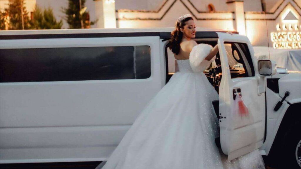 A beautiful bride in a stunning white gown stepping out of a luxurious white stretch limousine in Cambridge, Canada.